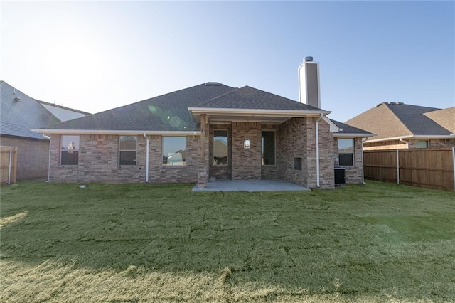 back of house featuring brick siding, a patio, a chimney, a lawn, and a fenced backyard