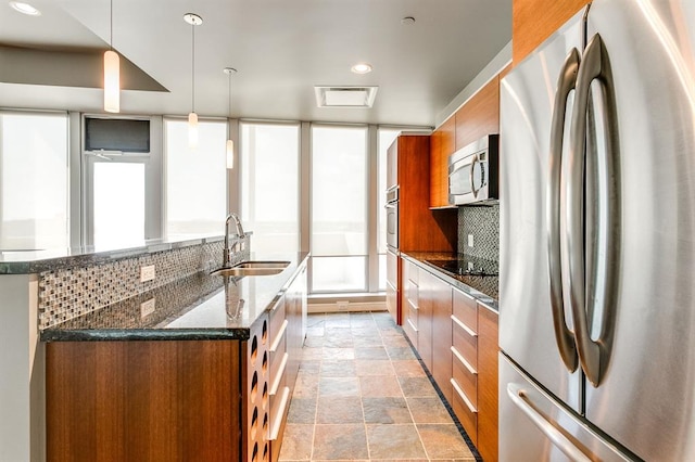 kitchen featuring sink, dark stone countertops, decorative backsplash, hanging light fixtures, and stainless steel appliances