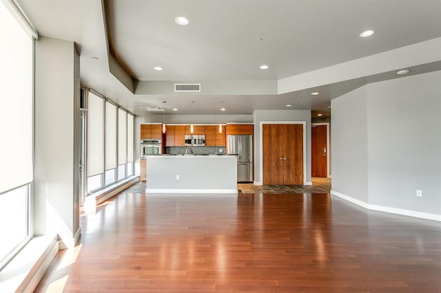 unfurnished living room featuring dark hardwood / wood-style flooring and a raised ceiling