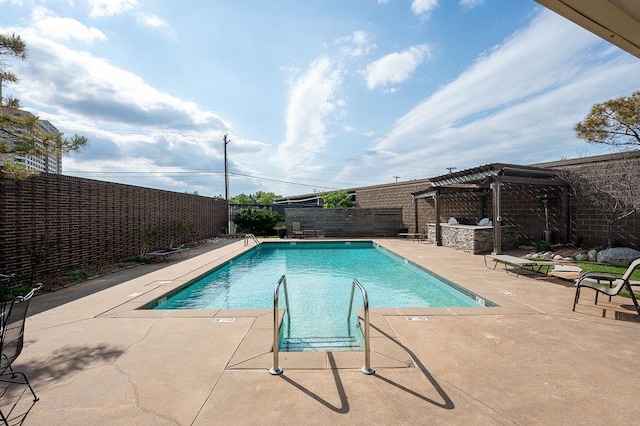 view of swimming pool featuring a patio, an outdoor kitchen, and a pergola