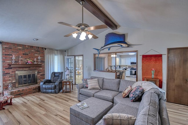 living area with light wood-style floors, a fireplace, vaulted ceiling with beams, and ceiling fan