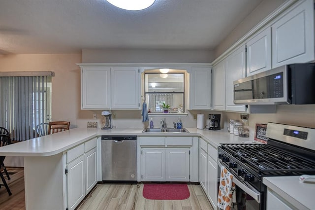 kitchen featuring a peninsula, appliances with stainless steel finishes, light countertops, and white cabinets