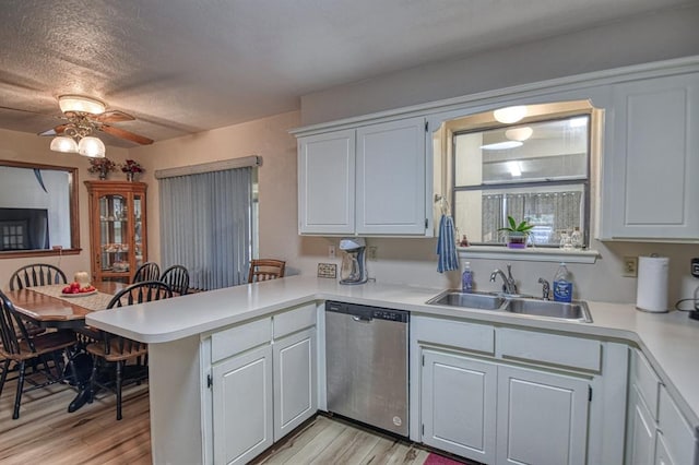 kitchen featuring dishwasher, a peninsula, light countertops, and white cabinetry