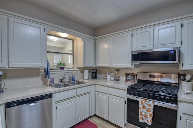 kitchen with white cabinetry, appliances with stainless steel finishes, light countertops, and a sink