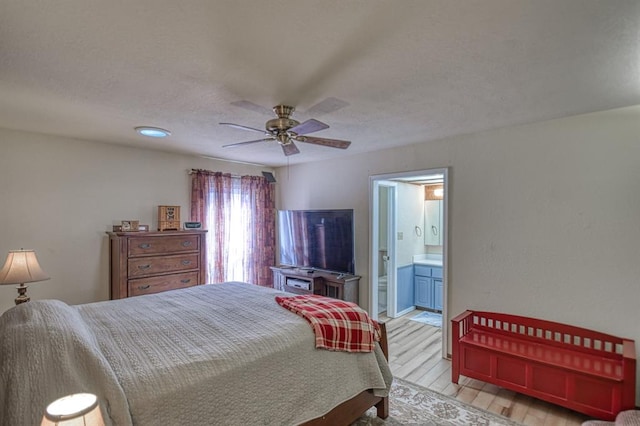 bedroom with light wood-style flooring, ceiling fan, and ensuite bathroom