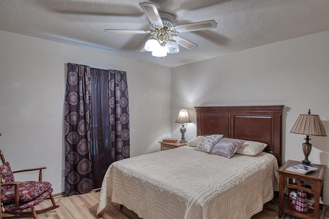 bedroom with light wood-style floors, a textured ceiling, and a ceiling fan