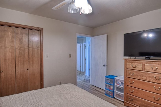 bedroom with light wood finished floors, a closet, and a ceiling fan