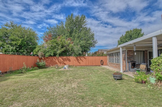 view of yard featuring a fenced backyard and a fire pit