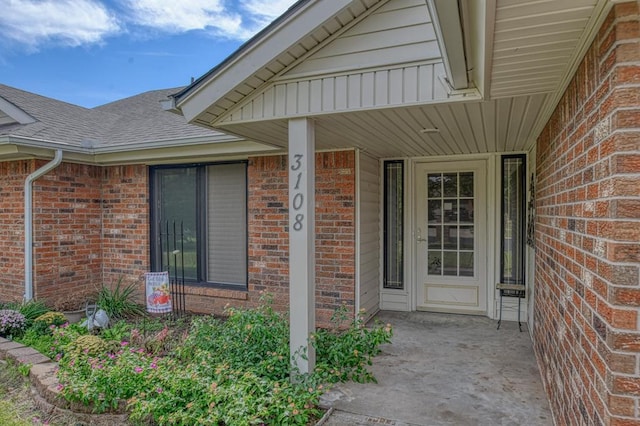 property entrance with brick siding and roof with shingles