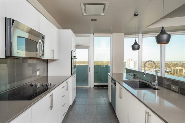 kitchen with stainless steel appliances, sink, hanging light fixtures, and white cabinets