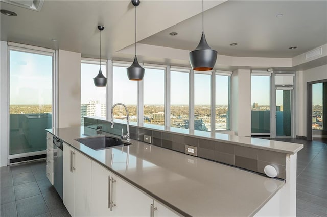 kitchen featuring white cabinetry, sink, a kitchen island with sink, and hanging light fixtures