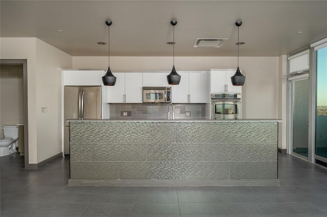 kitchen featuring sink, appliances with stainless steel finishes, white cabinets, pendant lighting, and backsplash