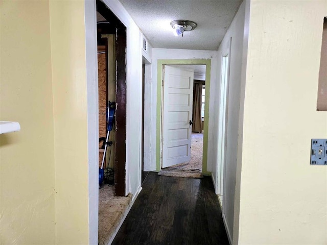 hall featuring dark wood-type flooring and a textured ceiling