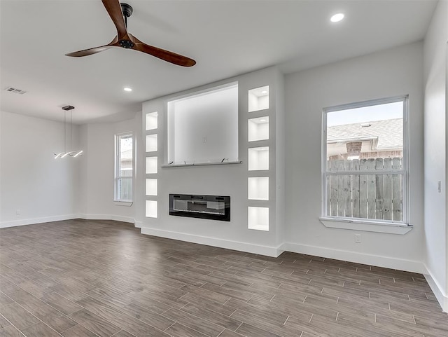 unfurnished living room featuring hardwood / wood-style floors, ceiling fan, and heating unit