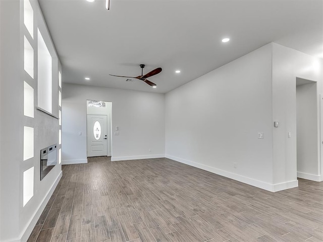 unfurnished living room featuring heating unit, ceiling fan, and light hardwood / wood-style flooring