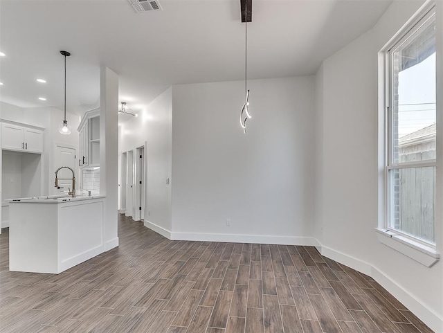 interior space featuring a wealth of natural light, dark hardwood / wood-style flooring, white cabinets, and hanging light fixtures