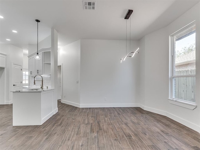 kitchen with white cabinetry, sink, dark hardwood / wood-style floors, kitchen peninsula, and pendant lighting