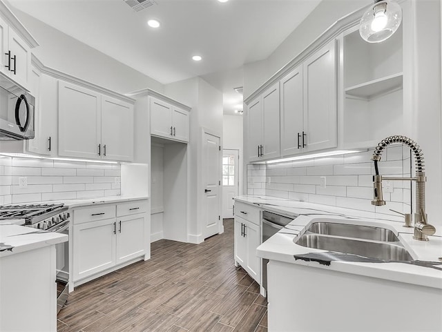 kitchen featuring hardwood / wood-style floors, white cabinets, sink, decorative backsplash, and stainless steel appliances