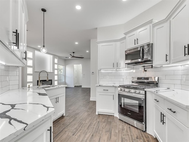 kitchen with pendant lighting, sink, ceiling fan, white cabinetry, and stainless steel appliances