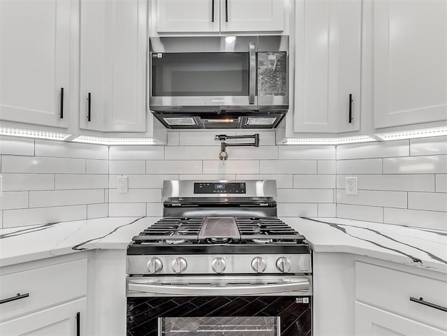 kitchen with decorative backsplash, white cabinetry, light stone countertops, and appliances with stainless steel finishes