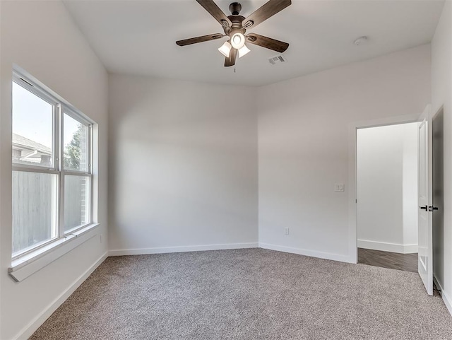 spare room with dark colored carpet and ceiling fan