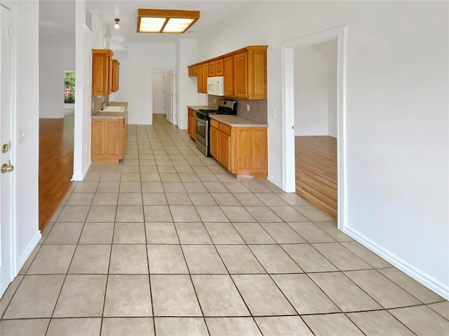 kitchen with gas stove, backsplash, and light wood-type flooring