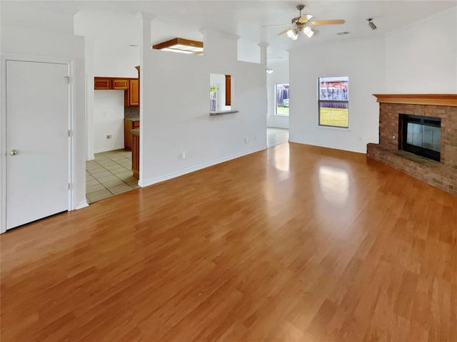 unfurnished living room with ceiling fan, a fireplace, and light hardwood / wood-style flooring