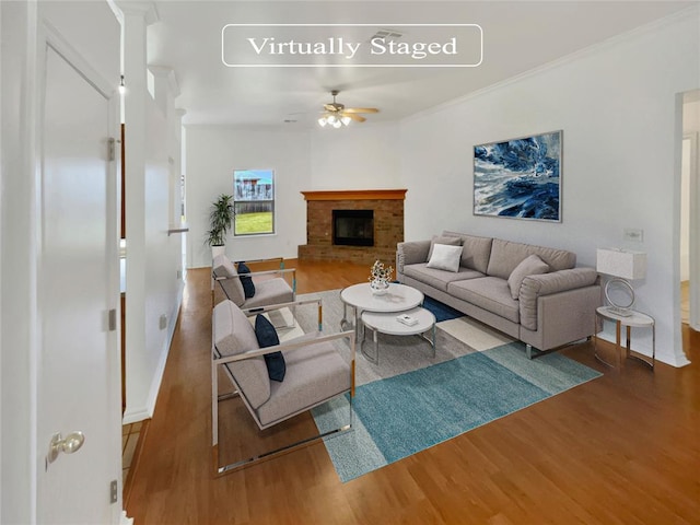 living room featuring crown molding, a fireplace, ceiling fan, and hardwood / wood-style flooring