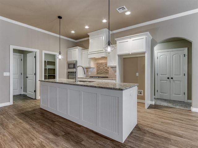 kitchen with white cabinetry, a center island with sink, stainless steel appliances, and light hardwood / wood-style floors