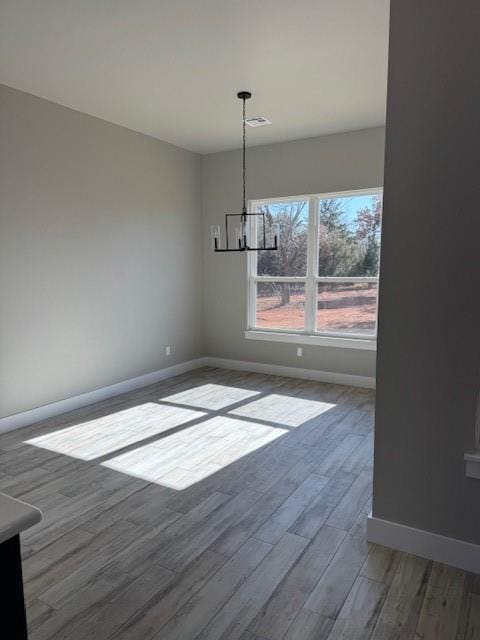 unfurnished dining area with a notable chandelier and hardwood / wood-style flooring