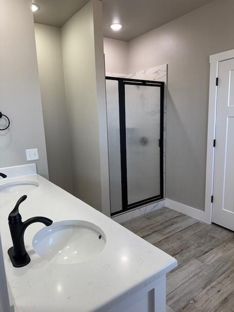 bathroom featuring a shower with shower door, hardwood / wood-style floors, and vanity