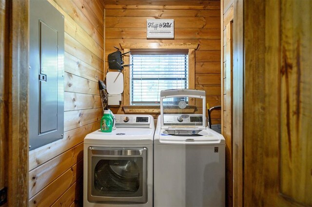 washroom featuring washing machine and dryer, wood walls, and electric panel