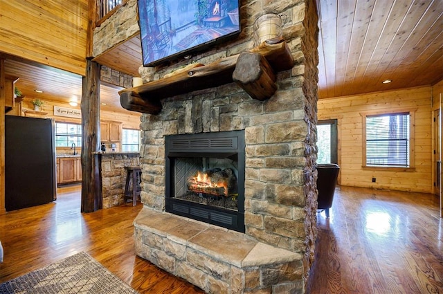 living room featuring wood walls, a stone fireplace, wood-type flooring, and wood ceiling