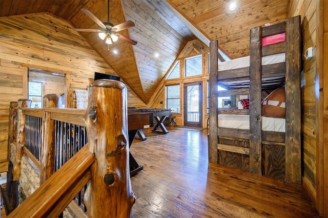 bedroom with multiple windows, wood walls, lofted ceiling, and hardwood / wood-style flooring