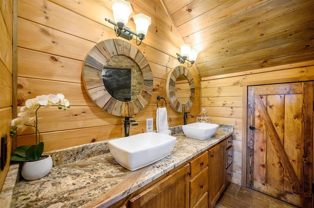 bathroom with vanity, lofted ceiling, wooden ceiling, wooden walls, and tile patterned flooring