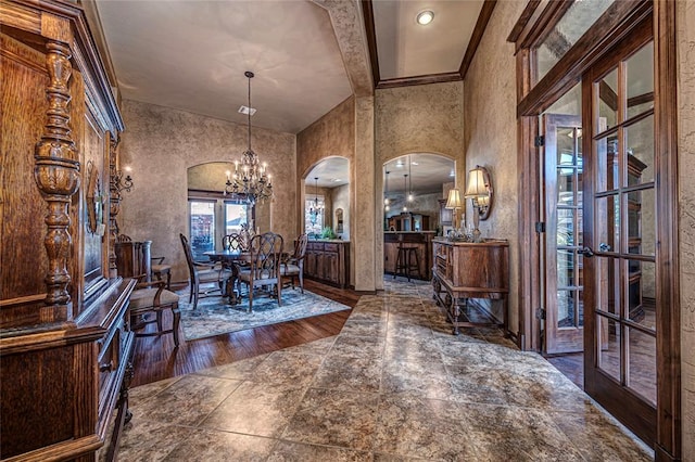 unfurnished dining area with french doors, ornamental molding, beam ceiling, a notable chandelier, and dark hardwood / wood-style floors