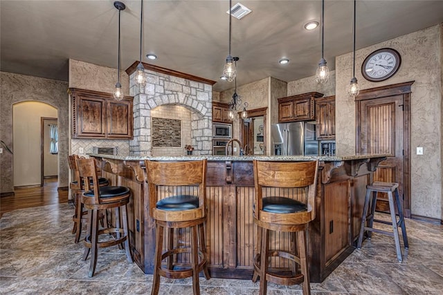 kitchen featuring a kitchen breakfast bar, a spacious island, stainless steel appliances, and decorative light fixtures