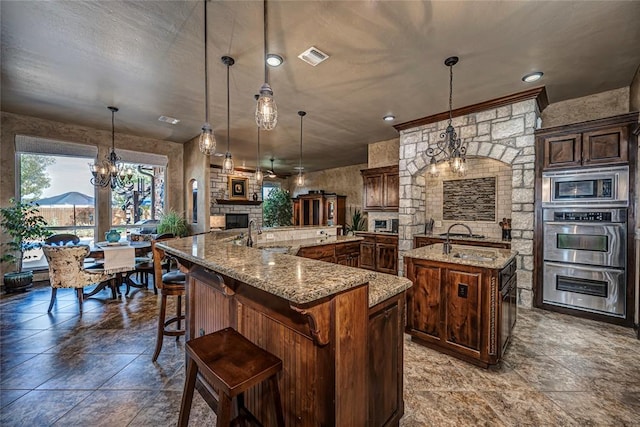 kitchen with stainless steel appliances, an inviting chandelier, a kitchen breakfast bar, a spacious island, and decorative light fixtures