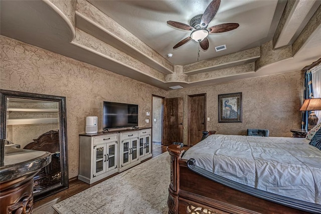 bedroom with a raised ceiling, ceiling fan, and dark hardwood / wood-style flooring