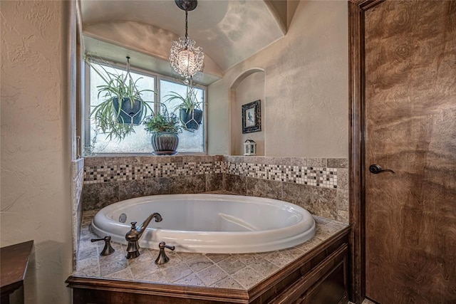 bathroom with a washtub, an inviting chandelier, and lofted ceiling