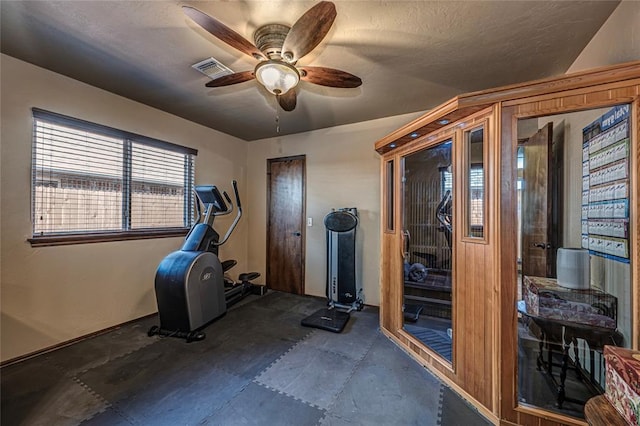 exercise room with a textured ceiling and ceiling fan