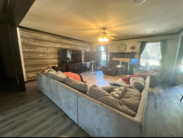 living room with wooden walls, crown molding, dark wood-type flooring, and a textured ceiling