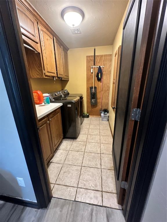 clothes washing area featuring cabinets, light hardwood / wood-style flooring, and washer and clothes dryer