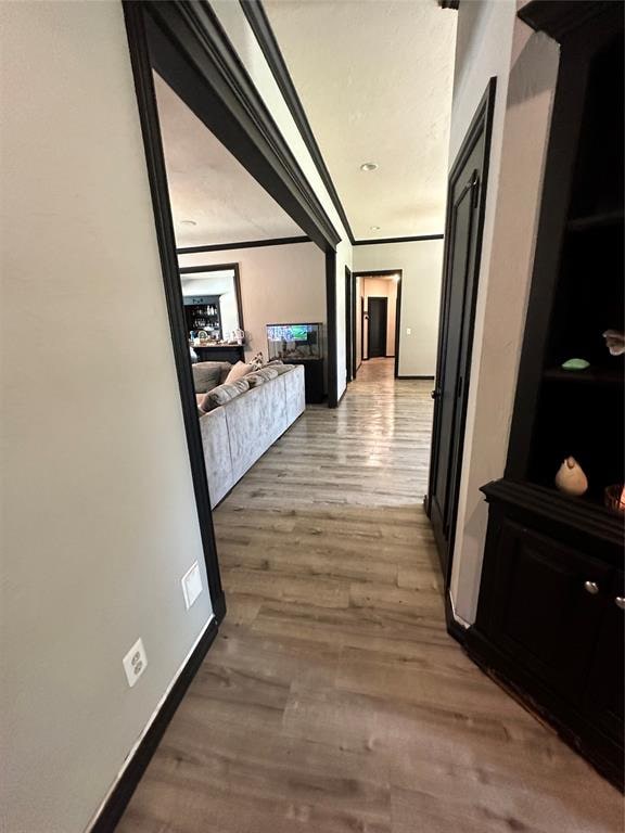 corridor with wood-type flooring and crown molding