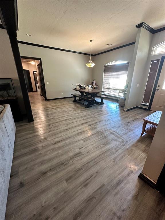 dining room with a textured ceiling, wood-type flooring, and ornamental molding