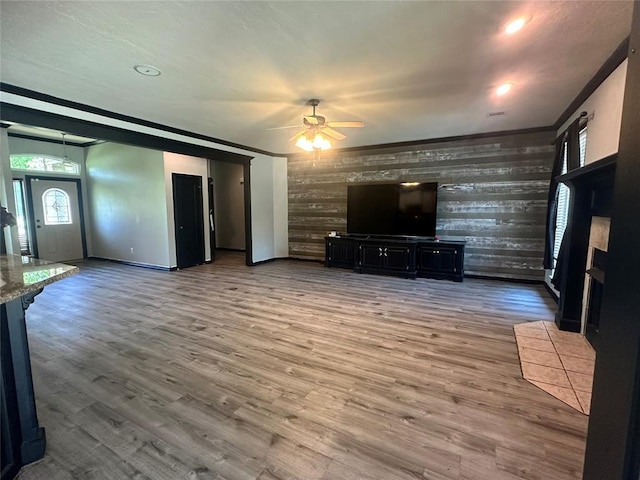 16355 Cobblestone Cir, Choctaw, OK 73020 - unfurnished living room with ceiling fan, wooden walls, wood finished floors, ornamental molding, and an accent wall
