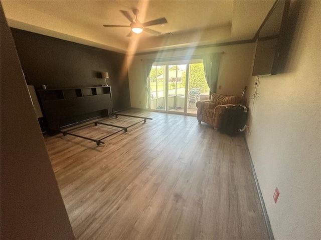 16355 Cobblestone Cir, Choctaw, OK 73020 - living room featuring a ceiling fan, wood finished floors, a textured wall, and a tray ceiling