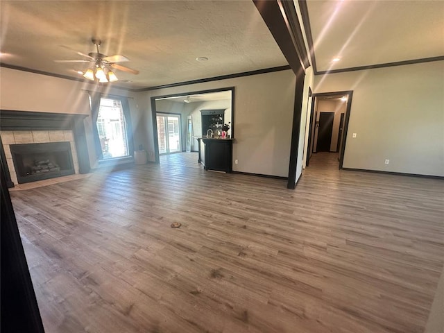 16355 Cobblestone Cir, Choctaw, OK 73020 - unfurnished living room with crown molding, a ceiling fan, wood finished floors, a fireplace, and a textured ceiling