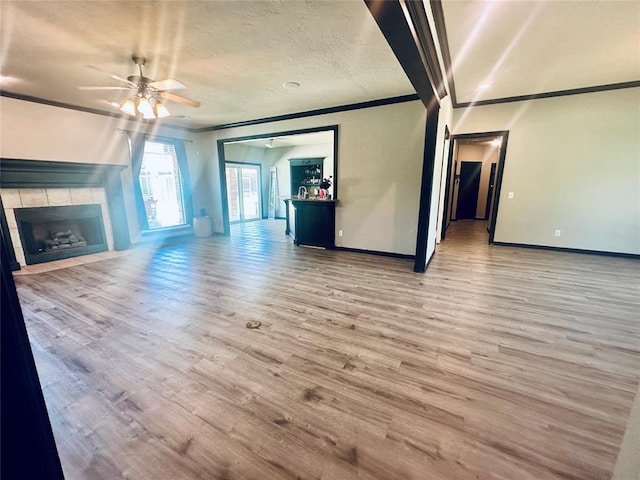 16355 Cobblestone Cir, Choctaw, OK 73020 - unfurnished living room featuring crown molding, a ceiling fan, wood finished floors, a fireplace, and a textured ceiling
