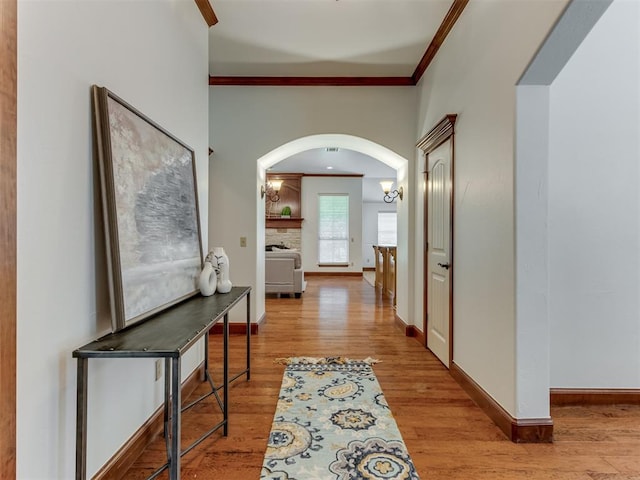 hallway with crown molding, an inviting chandelier, and light wood-type flooring